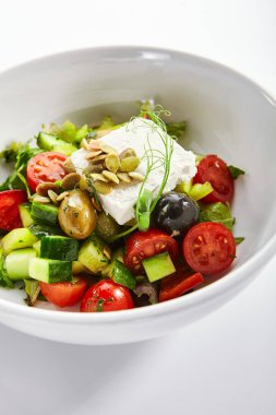 Beyaz kasede Yunan salatası. Dilimlenmiş taze sebze ve peynir. Geleneksel Yunan mutfağı servis edildi. Çiğ domates, salatalık ve zeytinyağı. Restoran yemekleri bölümü kapanıyor.