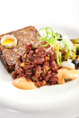 Biftek tartları yakın çekimdir. Soslu ve ekmekli lezzetli doğranmış et. Tabağında hardal ve yeşillik olan bir tabak. Lokanta lezzeti, haute mutfağı. Yemek sunumu, geleneksel tarif