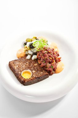 Biftek tartları yakın çekimdir. Soslu ve ekmekli lezzetli doğranmış et. Tabağında hardal ve yeşillik olan bir tabak. Lokanta lezzeti, haute mutfağı. Yemek sunumu, geleneksel tarif