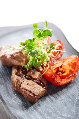 Domatesli ızgara mermer biftek. Kızarmış et, kesilmiş sebzeler ve bahçe teresi. Ahşap yüzeyde yeşillik ve sosla servis edilen lezzetli yemekler. Haute food, restaurant food