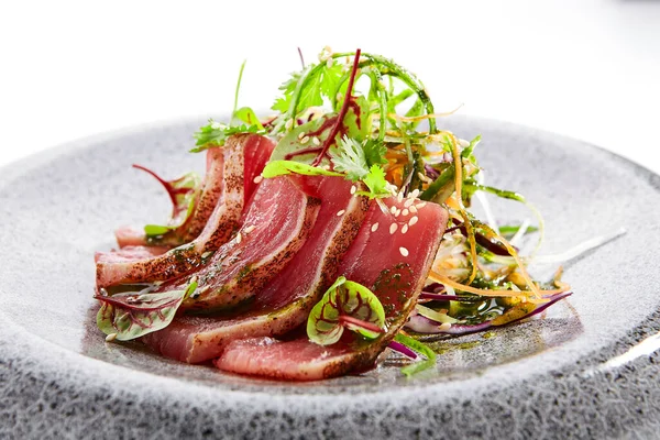 タタキマグロのクローズアップビュー 伝統的な日本料理法 皿の上のおいしい魚 緑と調味料でおいしいスライスした魚介類 アジア料理 料理の構成 レストラン料理 — ストック写真