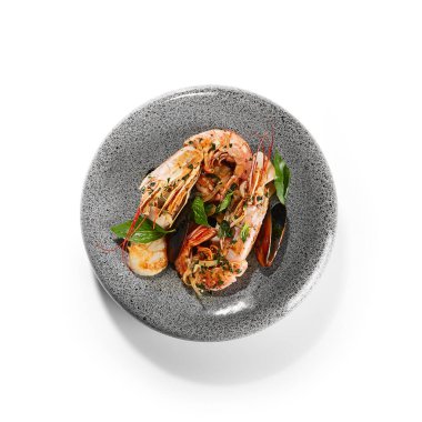 Deniz ürünleri çeşidi kapanıyor. Tabakta kırmızı karides, midye ve mürekkep balığı var. Baharat ve otlarla birlikte ızgara deniz ürünleri. Restoran deniz lezzeti, Akdeniz yemeği kompozisyonu.