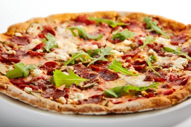 Biberli pizza dilimleri ve tabakta roka. Geleneksel İtalyan mutfağı, lezzetli fast food. Beyaz arka planda salam ve peynirli tuzlu yemek. Tabakta lezzetli pizzacı yemeği