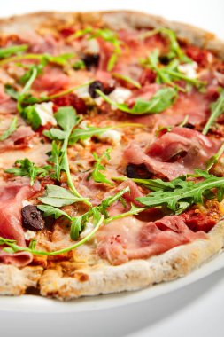 Jambonlu ve enginarlı pizza. Prosciutto ile nefis İtalyan yemeği. Geleneksel aromatik roka ve etle süslenmiş fırında yemek. Geleneksel Avrupa tarifi, aşçılık sunumu