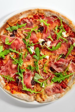 Jambonlu ve enginarlı pizza. Prosciutto ile nefis İtalyan yemeği. Geleneksel aromatik roka ve etle süslenmiş fırında yemek. Geleneksel Avrupa tarifi, aşçılık sunumu