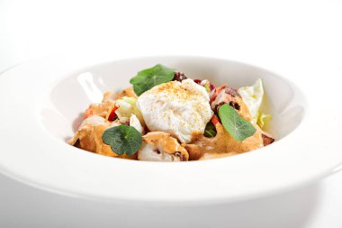 Beyaz kasede salata. Dilimlenmiş ahtapot ve kızarmış patates. Mayonez, domates baharatlı jajika ve ev yapımı füme biber sosu ile servis edilmiş. Restoran yemekleri tabakta. Kapatın.