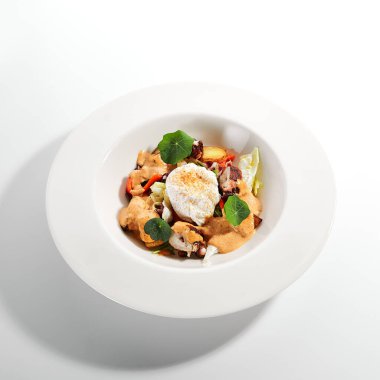 Beyaz kasede salata. Dilimlenmiş ahtapot ve kızarmış patates. Mayonez, domates baharatlı jajika ve ev yapımı füme biber sosu ile servis edilmiş. Restoran yemekleri tabakta. Kapatın.