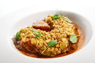 Baharatlı Osso Buco. Geleneksel İtalyan mutfağı servis edildi. Dana şiş, safran ve parmesan peynirli Farro. İtalyan restoranının yemek bölümü, ana yemek beyaz tabak.