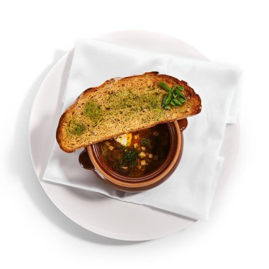 Ocakta pişirilmiş et çorbası ve enginar. Taze ekmek ve yeşillikle nefis bir çömlek. Geleneksel mutfak, restoran yemeği, akşam yemeği. Aromatik gulaş beyaz peçetede