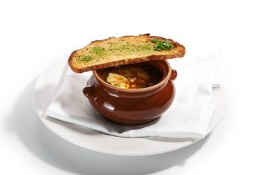 Ocakta pişirilmiş et çorbası ve enginar. Taze ekmek ve yeşillikle nefis bir çömlek. Geleneksel mutfak, restoran yemeği, akşam yemeği. Aromatik gulaş beyaz peçetede