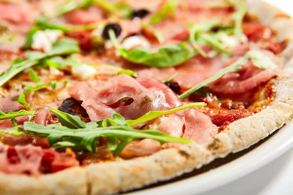 Pizza with parma ham and artichoke. Delicious italian meal with prosciutto. Traditional baked dish decorated with aromatic arugula and meat. Traditional european recipe, culinary presentation