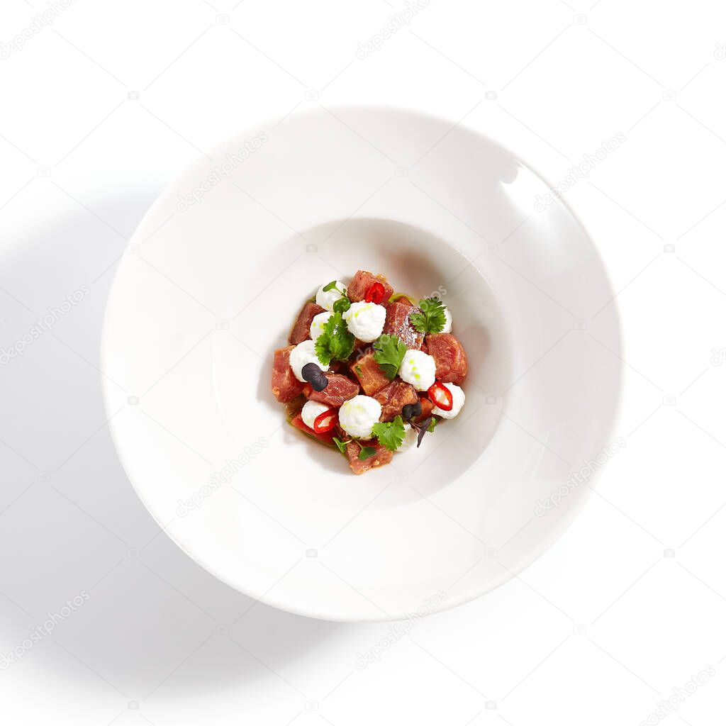 Tuna with stracciatella cheese and spicy sauce. Seafood with fresh green parsley in plate. Tasty fish with greenery on white background. Delicious restaurant food. Culinary composition