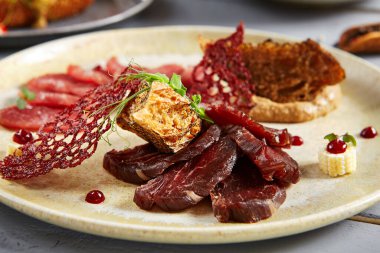 Bej seramik tabakta meze. Ekmek ve soğan soslu kurutulmuş et ve domuz eti. Bezelye dalları süslemeler. Avrupa mutfağı yemekleri, menü yemekleri, gurme aperatifleri.