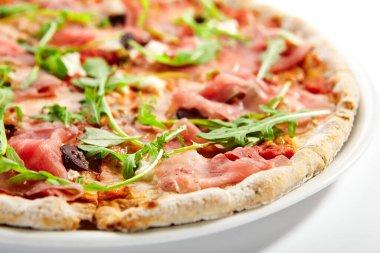 Jambonlu ve enginarlı pizza. Prosciutto ile nefis İtalyan yemeği. Geleneksel aromatik roka ve etle süslenmiş fırında yemek. Geleneksel Avrupa tarifi, aşçılık sunumu