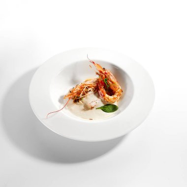 Krema soslu Langoustines. Lüks yemek servisi. Beyaz tabakta fesleğen yapraklı Norveç ıstakozu. Deniz ürünleri restoranının yüksek menüde yemek bölümü. Yemek nefis, ana yemek.