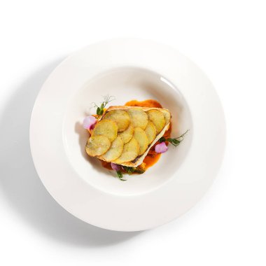Fırında patates dilimli kızarmış balık fileto. Lüks yemek servisi. Beyaz tabakta domatesli ve zeytinli balık yalıtılmış. Restoran yüksek menüde yemek bölümü. Yemek nefis, ana yemek.