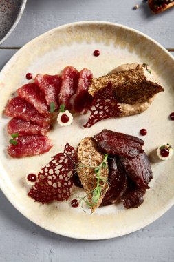 Bej seramik tabakta meze. Ekmek ve soğan soslu kurutulmuş et ve domuz eti. Bezelye dalları süslemeler. Avrupa mutfağı yemekleri, menü yemekleri, gurme aperatifleri.