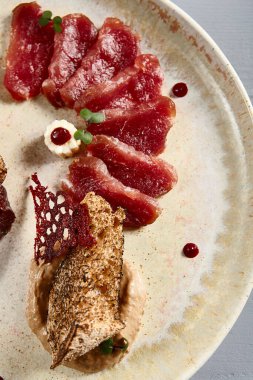 Bej seramik tabakta meze. Ekmek ve soğan soslu kurutulmuş et ve domuz eti. Bezelye dalları süslemeler. Avrupa mutfağı yemekleri, menü yemekleri, gurme aperatifleri.