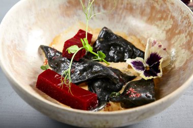 Bej kasede siyah midyeler. Yaban mersinli Ravioli ve kremalı sos. Bezelye dalları ve mor çiçek süslemeleri ile gurme aperatifleri. Şarküteri, deniz ürünleri.