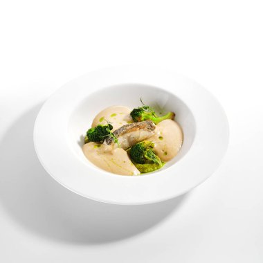 Deniz morina filetosu yakın çekim. Mutfak servisi. Beyaz tabak içinde balık ve fırında brokoli püresi malzemesi olan bir tabak. Lüks aşçılık. Restoran yemekleri, lezzetli yemekler, ana yemek.