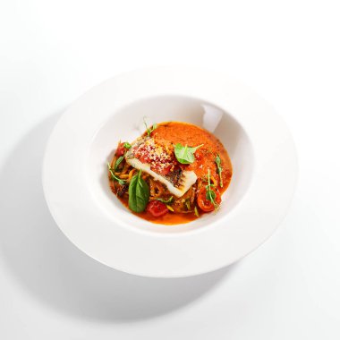 Halibut bifteği ve çıtır ekmek. Mutfak servisi. Balık filetosu ve beyaz tabakta domates soslu kabaklı spagetti. Restoran yemekleri, lezzetli yemekler, ana yemek.