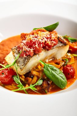 Halibut bifteği ve çıtır ekmek. Mutfak servisi. Balık filetosu ve beyaz tabakta domates soslu kabaklı spagetti. Restoran yemekleri, lezzetli yemekler, ana yemek.