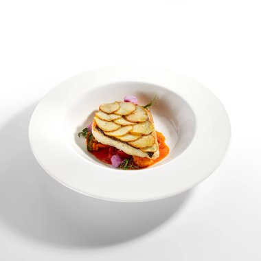 Fırında patates dilimli kızarmış balık fileto. Lüks yemek servisi. Beyaz tabakta domatesli ve zeytinli balık yalıtılmış. Restoran yüksek menüde yemek bölümü. Yemek nefis, ana yemek.