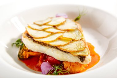 Fırında patates dilimli kızarmış balık fileto. Lüks yemek servisi. Beyaz tabakta domatesli ve zeytinli balık yalıtılmış. Restoran yüksek menüde yemek bölümü. Yemek nefis, ana yemek.