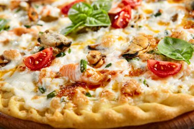 Tahta üzerinde deniz ürünleri pizzası. Geleneksel İtalyan mutfak fırını midye eti, somon filetosu, karides, kuşkonmaz, şampiyonlar, mozzarella ve beyaz soslu. Sıcak aperatif, pizza tabağı.
