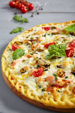 Tahta üzerinde deniz ürünleri pizzası. Geleneksel İtalyan mutfak fırını midye eti, somon filetosu, karides, kuşkonmaz, şampiyonlar, mozzarella ve beyaz soslu. Sıcak aperatif, pizza tabağı.