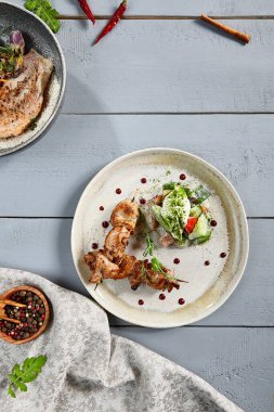 Bej tabakta ev yapımı taze sebze salatasıyla tavuk kalçası barbeküsü. Yeşillik ve sebzeli kızarmış et. Sıcak aperatif, aperatif, restoran yemeği, diyet shashlik.