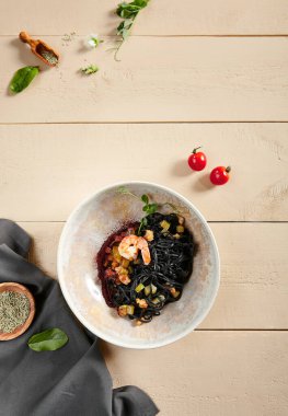 Bej kasede karides ve kabaklı siyah spagetti. Mürekkepbalıklı makarna yakından. Lezzetli şarküteri, servis edilen restoran yemeği, deniz ürünleri ve sebzeli lezzetli erişte.