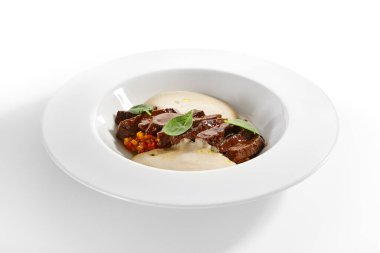 Sığır kalbi yahnisi ve sebzeler. Kızarmış et ve sebzeli risotto beyaz arka planda izole edilmiş tabakta servis edildi. Gurme aşçılık, gastronomi. Restoran yemekleri, ana yemek.