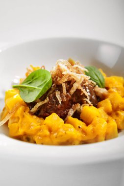 Kurutulmuş kereviz köklü biftek. Lüks yemek servisi. Beyaz tabakta sebzeli et ve parmesan peyniri. Restoran yüksek menüde yemek bölümü. Yemek nefis, ana yemek.