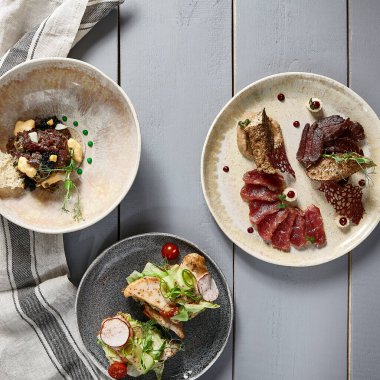 Seramik tabaklarda et aperatifleri. Baget ve soğan soslu kurutulmuş sığır eti, hindili bruschetta, biftekli tartar. Avrupa mutfağı yemekleri, restoran yemekleri
