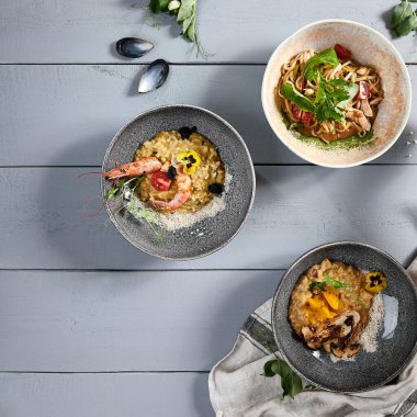 Seramik kaselerde risotto ve erişte. Et ve deniz ürünleri ile yükseltin, tavuklu makarna. Lezzetli şarküteriler, İtalyan ve Asya mutfağı yemekleri, restoran yemekleri.