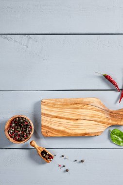 Tahta kesme tahtası ve masa manzaralı yeşillik. Mutfak eşyaları ve mavi renkli ahşap masalarda çiçek açan bitki dalları. Mutfak eşyaları ve yerde botanik dekoratif öğeler