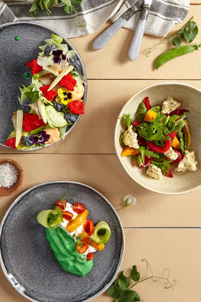 Seramik tabaklarda balık ve sebze salatası. Deniz ürünleri ve sebzeler, sağlıklı beslenme, beslenme. Vejetaryen yemeği, ahşap masada servis edilen restoran yemekleri, köy usulü servis.