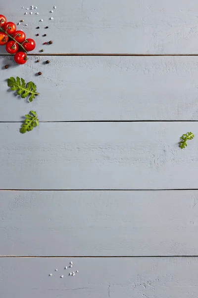 木製のテーブルの上からの眺めでチェリートマトとスパイス 野菜や緑の葉 黒コショウ 板に塩 野菜と風味豊かな素朴なスタイルの背景装飾 — ストック写真
