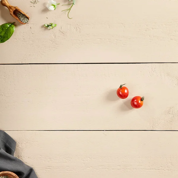 Flavoring and napkin on wooden table top view. Crumpled tablecloth, spices in wooden bowl and bucket, flower buds, greenery and tomatoes on wooden boards. Rustic style decoration, table setting