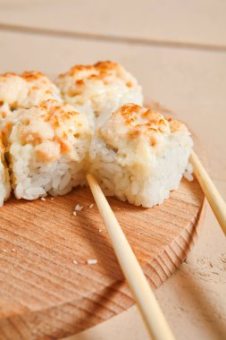 Ahşap tahta manzaralı fırınlanmış karides ruloları. Lezzetli sıcak suşi, soya soslu somon filetosu ve sashimi. Asya yemekleri, geleneksel Japon yemekleri, çubuklu deniz ürünleri.