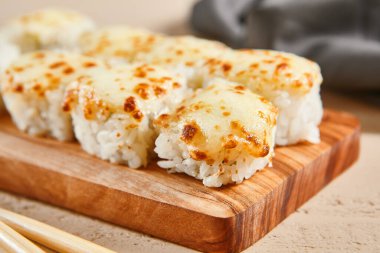 Ahşap tahta manzaralı fırınlanmış karides ruloları. Lezzetli sıcak suşi, soya soslu somon filetosu ve sashimi. Asya yemekleri, geleneksel Japon yemekleri, çubuklu deniz ürünleri.