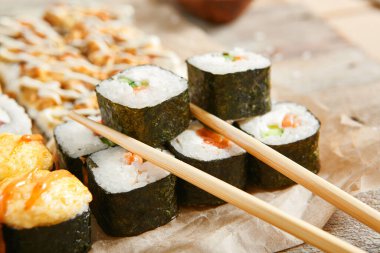 Çubuklu pn parşömeni yuvarla. Lezzetli suşi, Asya mutfağı, sağlıklı beslenme, pirinç ve balıklı geleneksel Japon yemekleri. Deniz ürünleri, restoran yemekleri.