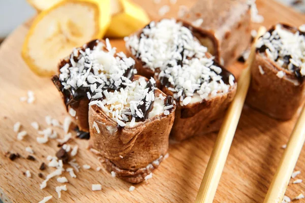 キウイとチョコレートパンケーキ 木製のボード上のビューでココナッツフレーク マスカルポーネチーズ クリームチーズ チョコレートトッピング 練乳で春巻き バナナの装飾と甘い食事 — ストック写真