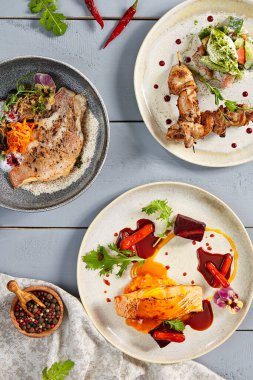 Seramik tabaklarda sıcak yemekler. Avrupa mutfağı, et ve sebzeli deniz ürünleri. İştah açıcı şarküteriler, gastronomi, restoran yemekleri ve ahşap masada lezzet.