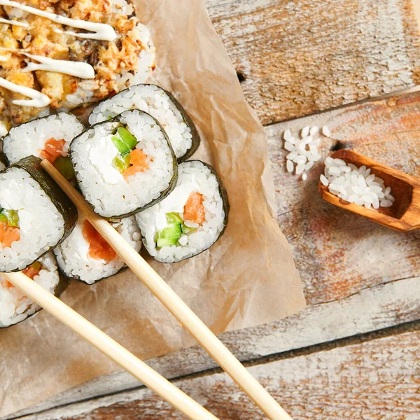 Roll set pn parchment with chopsticks. Delicious sushi, asian cuisine, healthy nutrition, traditional japanese food with rice and fish close up. Served seafood, restaurant meal