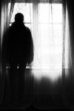 Bir pencere önünde duran bir kişi sillhouette.