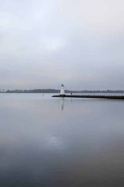 Fyren på bryggan reflekterar i lugnt vatten. — Stockfoto