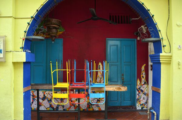 Colorful chairs on a wooden table in front of old shop, Singapore