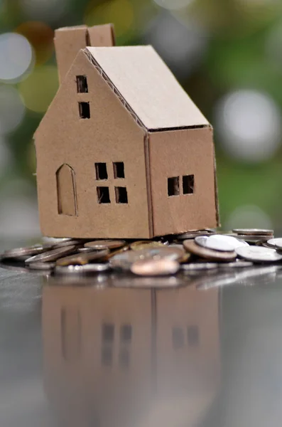 Model of house with coins on wooden table — Stock Photo, Image